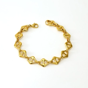 Détail macro d'un bracelet doré poli à maillons géométriques creux sur fond blanc pur