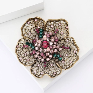 Vintage floral rhinestone brooch with pink and green stones on a gold-tone metal base