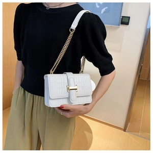 Detail of white crocodile pattern crossbody bag with golden H buckle worn by a model