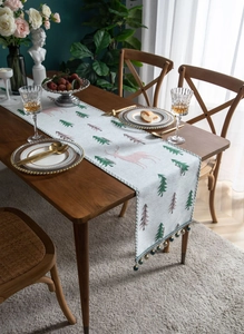 Close-up of Christmas table runner featuring jacquard reindeer patterns and tassel fringe