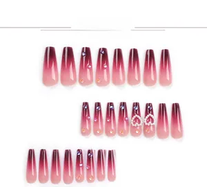 Detail of long coffin nails with burgundy gradient finish plus rhinestones and pearls