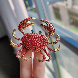 Macro shot of crab brooch featuring red rhinestones and golden alloy detail