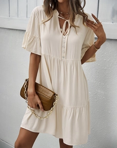 Détail de la robe beige à manches courtes avec col en V, bouton et ourlet à volants
