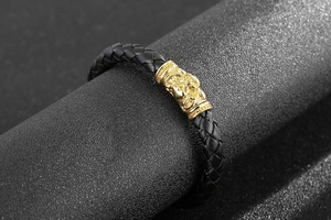 Detailed close-up of a braided leather bracelet with golden Pixiu metal charm