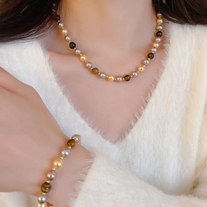 Gros plan détaillé du collier et du bracelet en perles d'œil de tigre portés par un modèle