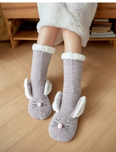 Close-up of gray knit bunny floor socks with plush ears and embroidered face details