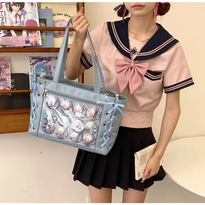 Detail of light blue ita bag with transparent window displaying anime pins and character badges