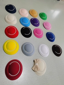 Top view of eighteen colorful pearl-rimmed fascinator hats arranged on a grey surface
