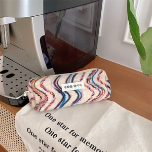 Détail d'une trousse tricotée aux motifs de vagues arc-en-ciel sur une table en bois