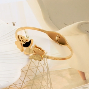 Detail of gold butterfly bangle featuring black enamel and glitter textured butterfly accents