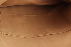 Detail shot of the interior brown fabric lining and a small open pocket of the woven bag