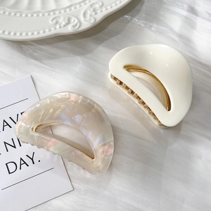 Close-up of aurora pearl and ivory white acetate hair claws on a romantic fabric background