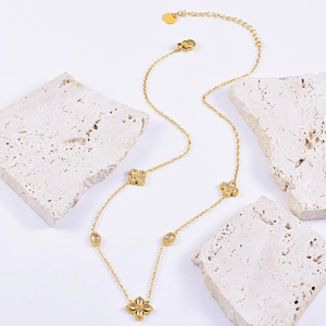 Elegant gold necklace with four-petal flower pendant and oval zircon on travertine base