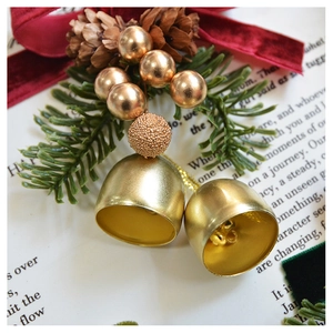 Macro detail of Christmas ornament with gold bells, pine cones and red velvet bow