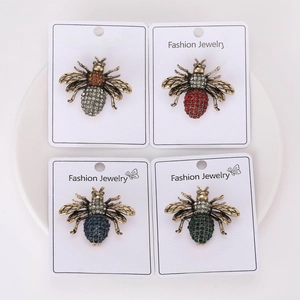Detailed view of four vintage bee brooches with colorful rhinestones on white card display