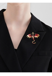 Detail of red and orange enamel dragon brooch with gold frame on a black suit lapel