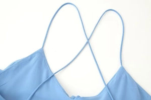 Close-up of light blue dress showing intricate cross strap details and fabric texture