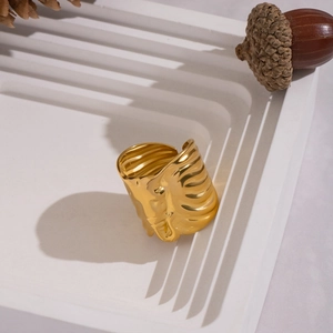 Detailed view of wide gold ripple ring with metallic texture on white display