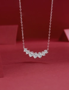 Detail view of a 925 sterling silver necklace featuring seven round cut stones on red background
