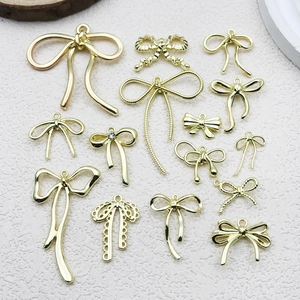 Golden bow-knot charms collection for DIY jewelry making on white textured background