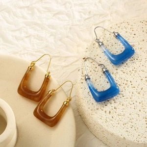 Macro shot of U-shaped resin hoop earrings with marble texture on a stone base