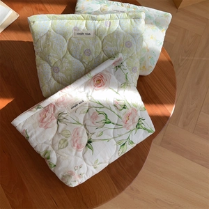 Detailed view of three floral quilted cotton pouches on a rustic wooden table in sunlight