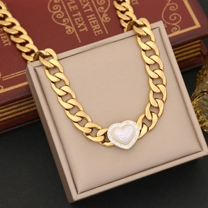 Detailed view of a gold Cuban chain necklace with a heart-shaped white shell pendant inlay