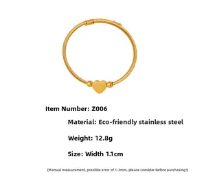 Detail view of golden stainless steel cable bracelet with heart pendant and bead accents