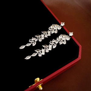Detailed view of silver leaf tassel earrings with sparkling zircons on red jewelry box