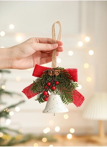 Detail of white metal bell with red burlap bow, pine needles and berries for Xmas decor