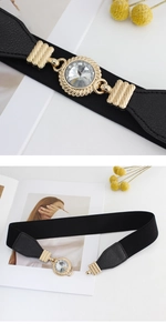 Detail of black elastic belt featuring a gold buckle with a large sparkling crystal