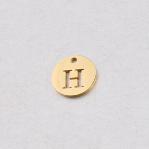 Détail d'un pendentif rond doré en acier inoxydable de 12 mm avec lettre H ajourée
