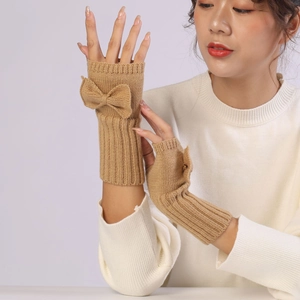 Detailed knit texture of ginger fingerless gloves with a decorative bow and ribbed cuff