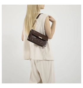 Sac bandoulière tendance en cuir marron foncé avec chaîne dorée sur tenue beige