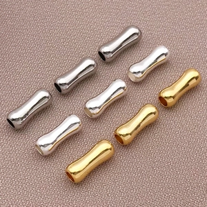 Dettaglio di perline metalliche curve lucide in finiture oro, argento e canna di fucile