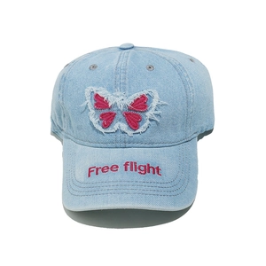 Detail of light blue denim baseball cap with butterfly patch and Free flight embroidery