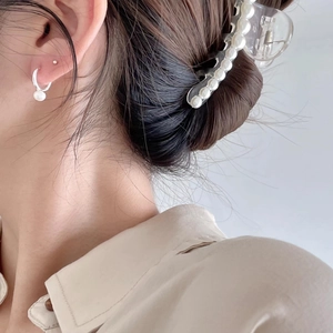 Close-up of elegant pearl drop earrings and matching hair claw clip on female model
