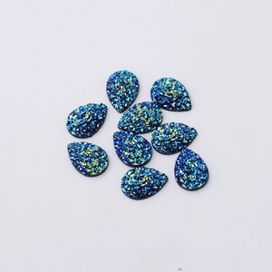 Flat lay of drop-shaped resin jewelry charms with sparkling blue, green, and yellow glitter