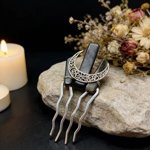 Macro shot of a bohemian moon hair comb with black crystal stones on a natural rock surface