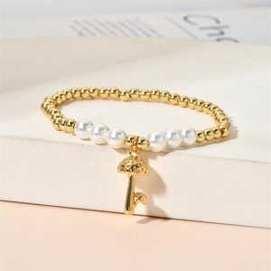 Detail of gold beads and white pearl bracelet with a mushroom pendant on white stairs
