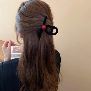 Close-up of black flocked hair claw clip with large red bead decoration on long hair