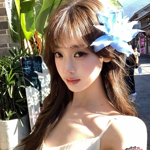 Elegant blue fabric flower hair clip worn by model in a stylish outdoor street setting