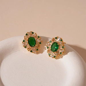 Detailed macro view of vintage gold stud earrings with oval green gemstone and white zircons
