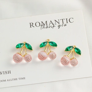 Macro view of pink crystal cherry pendants with green leaves and gold metal link stems