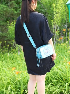 Outdoor lifestyle view of light blue soccer print crossbody bag with dual zippers
