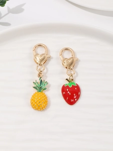 Close-up of enamel pineapple and strawberry charms with gold heart-shaped lobster clasps