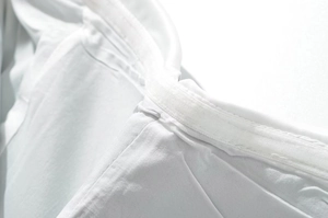 Detail of white fabric showing fiber texture, velcro strap and double stitched seams