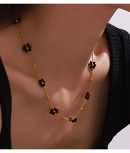 Détail d'un collier en titane plaqué or avec de petites perles florales noires