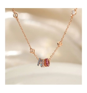 Detail of rose gold necklace featuring five colorful pavé-set rings and zircon accents