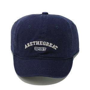 Detail of white letter embroidery ARETHEGREAT SPORT on a navy cotton baseball cap